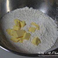 将黄油块放入上一步的粉状混合物中，用揉搓压扁的方式，让黄油与面粉充分融合。
