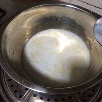 把泡软的吉利丁片倒入牛奶和白砂糖的混合液中，迅速搅拌。吉利丁片受热很快就融化了