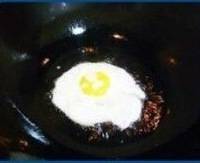 将爆葱花姜末的油倒入锅中 打入鸡蛋 煎至下层表面成形
