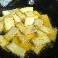 豆腐切片进油锅煎炸至金黄色，捞起沥干多有的油备用。
