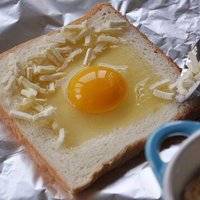 在蛋清和面包边之间铺上一层芝士碎