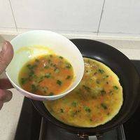 搅打好的蛋液加萝卜干粒、胡萝卜粒、葱花混合均匀。平底锅放少量油，缓慢倒入混合好的蛋液，均匀在锅里摊一层，火力一直保持中火。