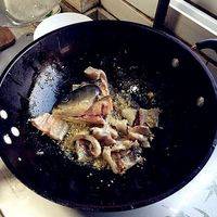 热锅下油烧热后下蒜末姜末，将鱼头鱼骨下锅炒一下倒出备用。