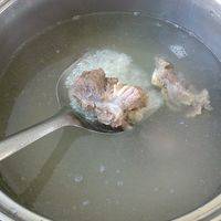 用适量的水煮沸，加进米与猪骨



