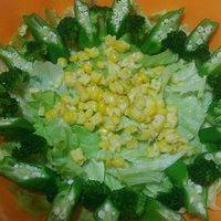焯烫好的秋葵和西兰花摆入沙拉碗中，蒸熟的玉米，用刀切下玉米粒撒入碗中。