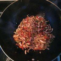 待鱿鱼须炒至金黄色后放入准备好的乌江榨菜，红椒丝继续翻炒。