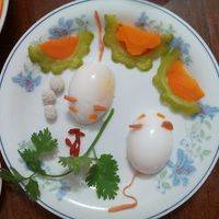 鸡蛋煮熟切半 胡萝卜装饰眼睛，火腿削条装饰尾巴。苦瓜胡萝卜摆盘 放入香菜
