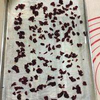 烤盘内铺上一层烘焙纸，均匀撒上蔓越莓干。