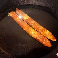 把香肠放水中煮10分钟捞出，待其凉后切片待用，生菜切碎备用。