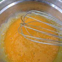 用手动打蛋器把蛋黄打到颜色发白。慢慢加入玉米油，温水和牛奶。