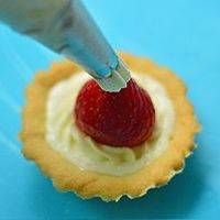 草莓切去底部，放在奶油上，形成帽子的形状