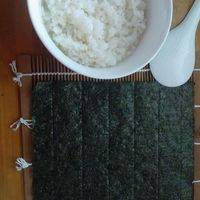 在竹帘上铺好紫菜，米饭里少量的加一点寿司醋，搅拌均匀。