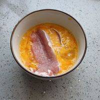 把鸡蛋打入碗中打散，放入猪肉沾上蛋液。