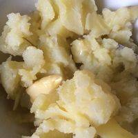 土豆中加入黄油，与黄油混合，用勺子捣碎成泥