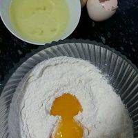把玉米粉加入面粉中，再加入分离出来的两个蛋黄，加入极少的盐，用温水和面