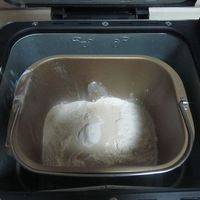   将高筋面粉、发酵粉和水放入面包机中，