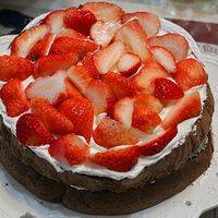 再盖一片蛋糕，同样铺满草莓，抹适量的奶油。