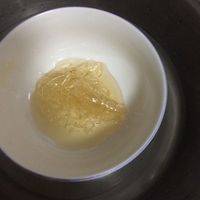 慕斯制作步骤2：两片吉利丁片加入自来水中泡软，隔水融化成液体，倒入搅拌好的淡奶油中（上个步骤），边倒边放入适量黄桃粒。放入冰箱冷藏2小时