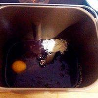 面包桶内先安装搅拌刀，先倒入冷却的巧克力水，在四周分别加入白糖、盐、奶粉、鸡蛋