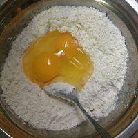 将鸡蛋打入进筛后的面粉、用少许温水溶开酵母倒进面粉里