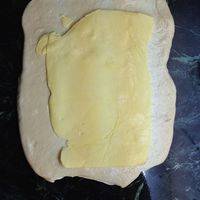 把揉好的面团在冰箱中冷冻30钟以上，100g的黄油擀成片状，放在冷冻好擀成方块的面饼上，相互折叠，再擀，使之变成一层面一层油状。